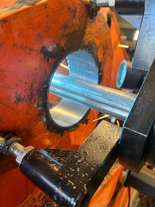 A boring bar passed through the bore of an orange machine casting with the cutting head mounted mid span