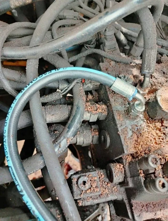 Close inspection of hydraulic hoses and a valve bank contaminated with dust and oil