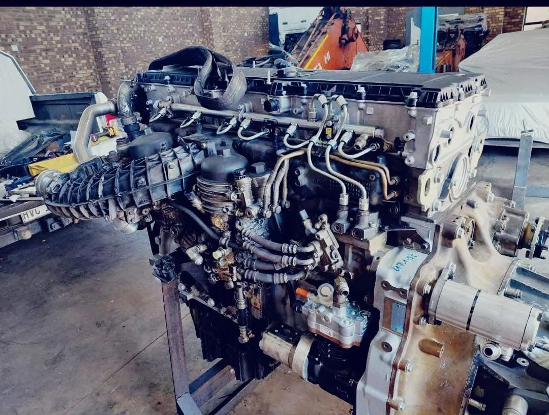 A heavy truck engine and gearbox assembly on a workshop stand with fuel lines fitted