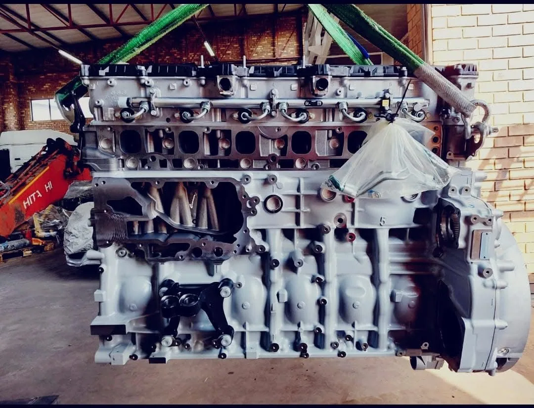 A reconditioned six-cylinder engine block suspended on lifting slings inside the workshop