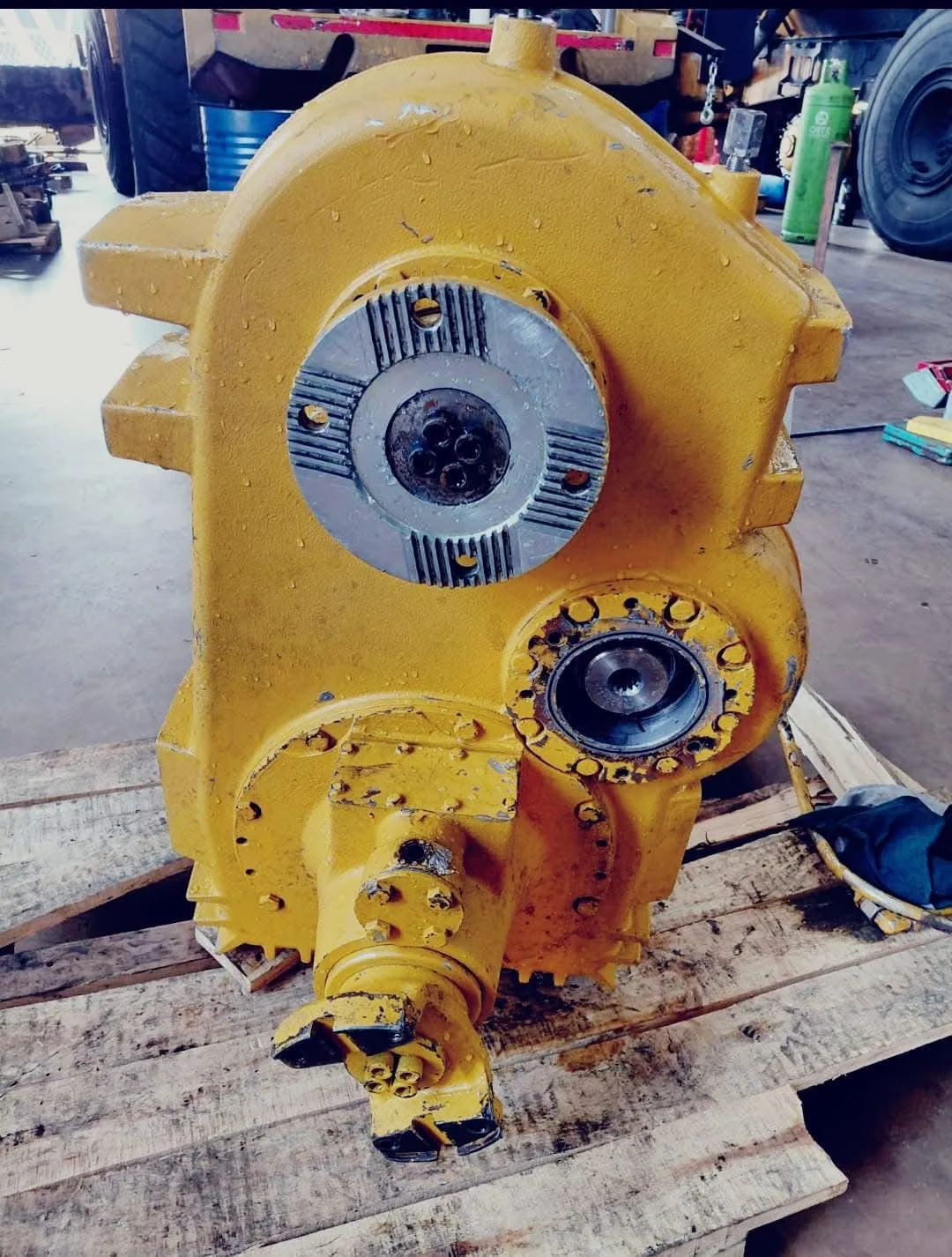 A large yellow transmission housing on a pallet with the input hub exposed